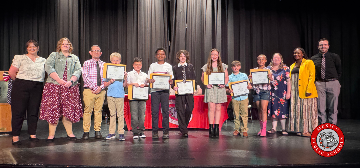Group of students on stage, holding certificates